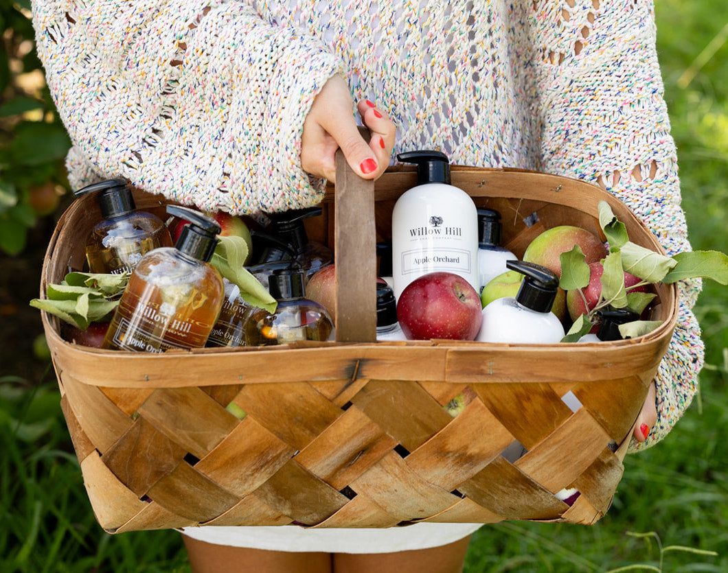 Woman holding a basket full of Willow Hill Soap Company products and fresh apples. 