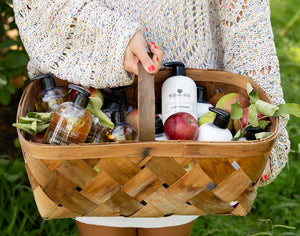Woman holding a basket full of Willow Hill Soap Company products and fresh apples. 
