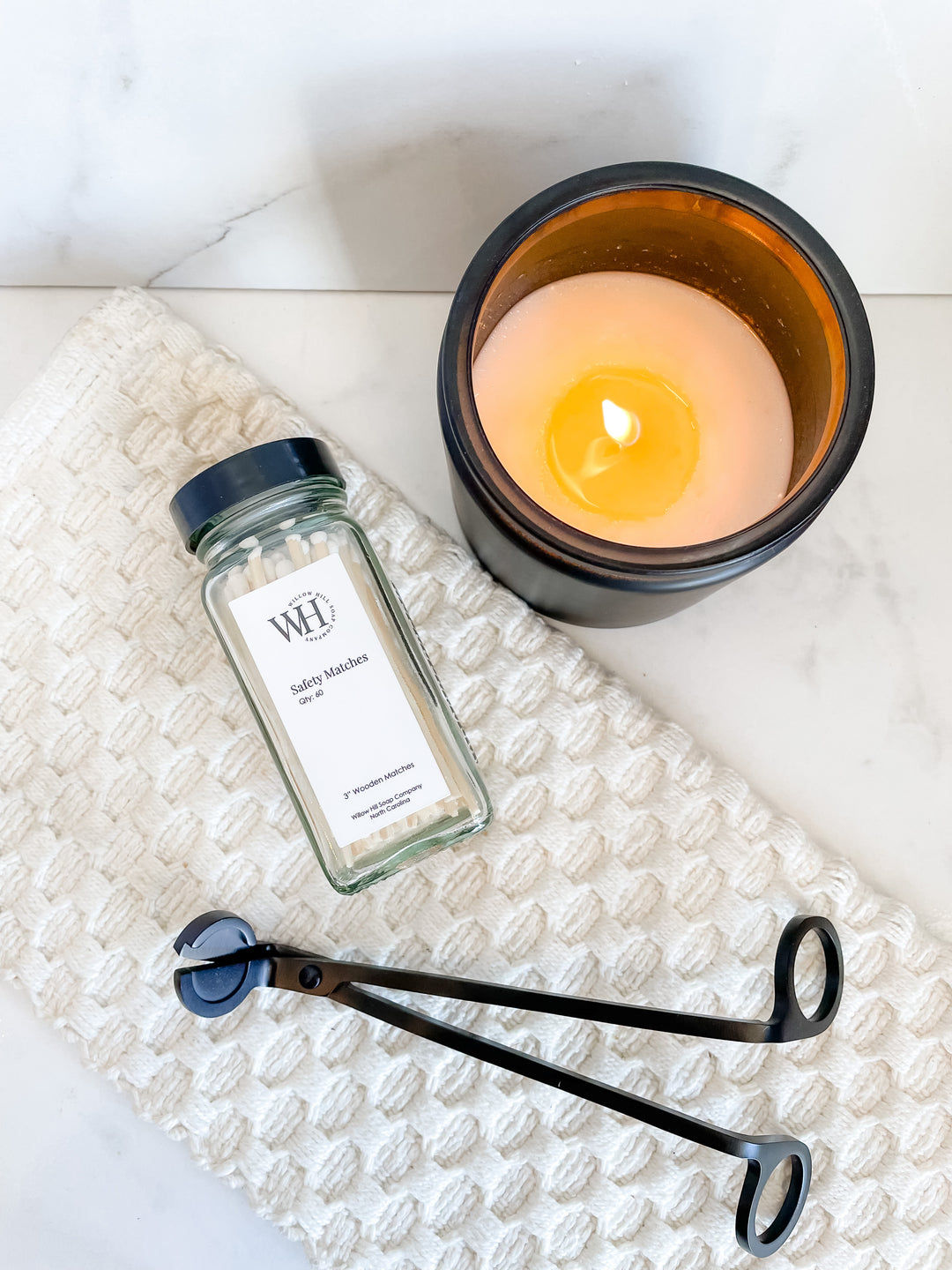 Safety matches alongside a lit candle and a wick trimmer 